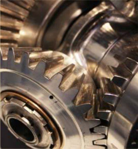 A machined gear train sealed under a self-healing waxy film.